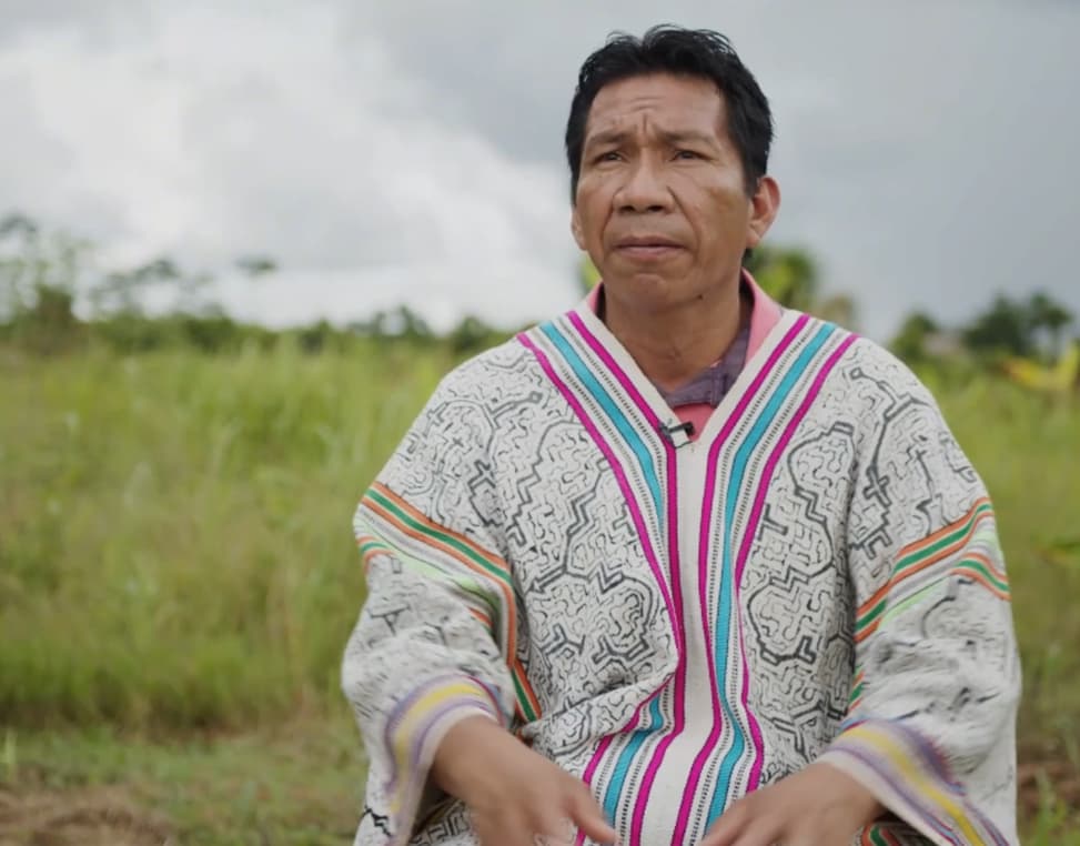 Luis, seated in a field in the Peruvian Amazon